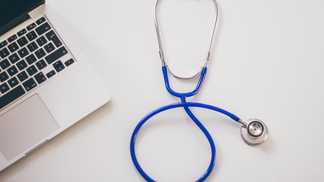 Stethoscope next to a laptop on a white desk