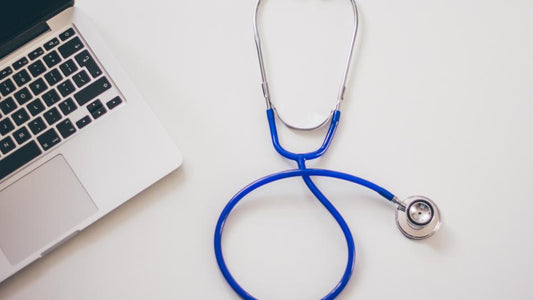 Stethoscope next to a laptop on a white desk