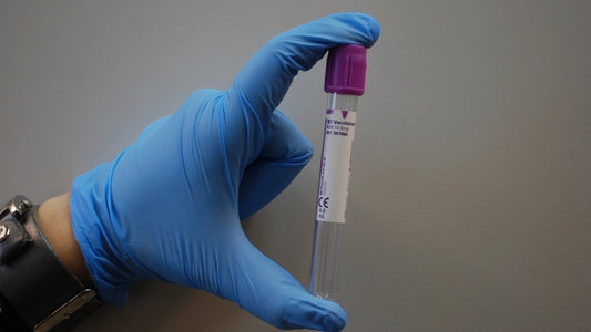 Gloved hand holding a blood collection tube